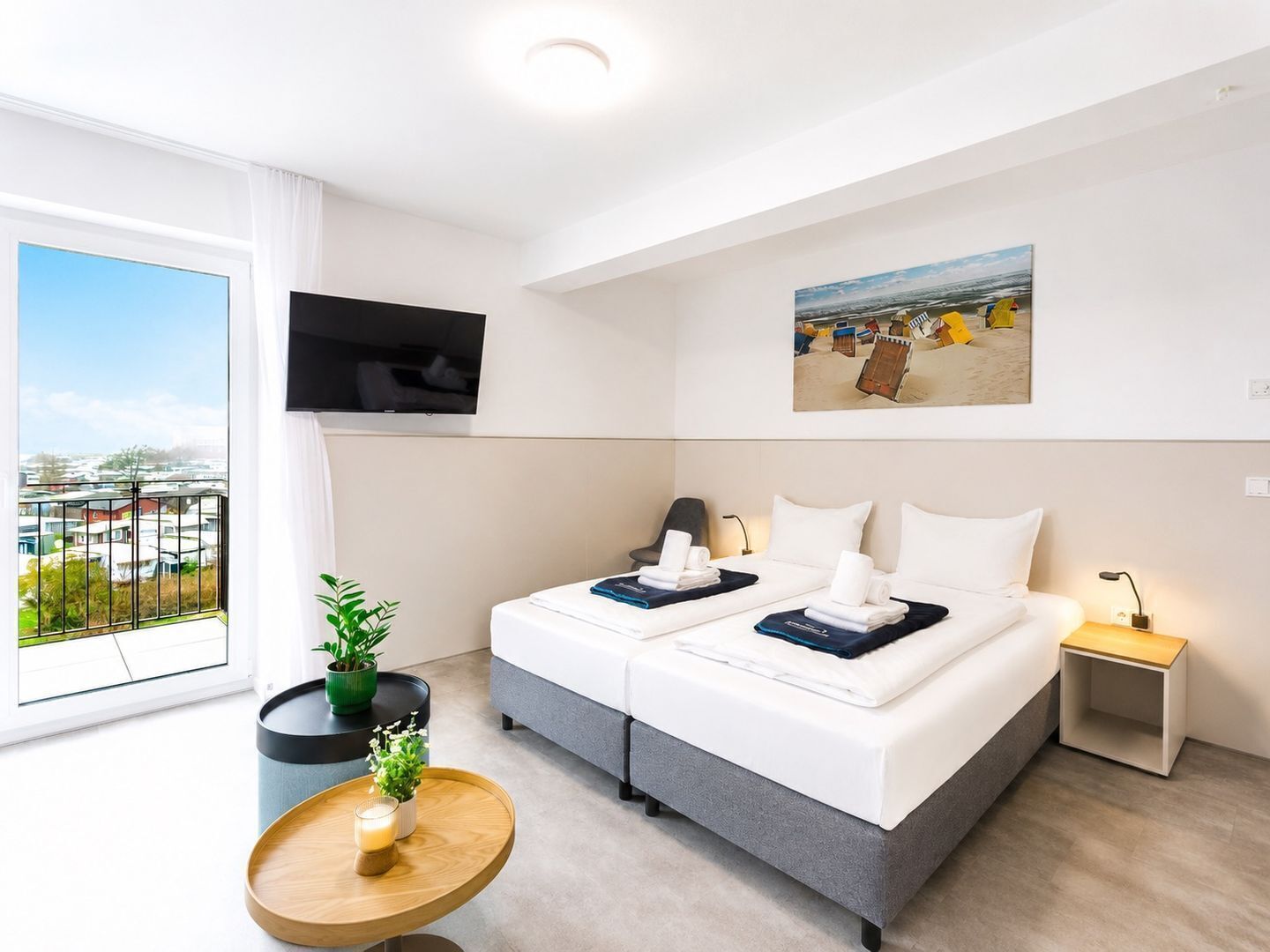 Ein Hotelzimmer mit Bett, Fernseher, einem kleinen Tisch mit Pflanze und Blick auf die Stadt.