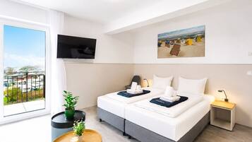 Ein Hotelzimmer mit Bett, Fernseher, einem kleinen Tisch mit Pflanze und Blick auf die Stadt.