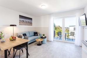 Ein modernes Wohnzimmer mit einer Couch, einem Esstisch und einem Balkon mit Sitzgelegenheiten.