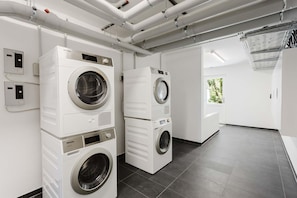 A modern laundry facility with stacked washers and dryers, a control panel, and a view of the outdoors. - MEERholung Vacation Rental 1.8 for up to 4 people, 400 m from the beach - House (Cuxhaven)