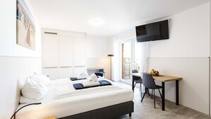 Een hotelkamer met een bed, bureau, stoel, televisie en raam.
