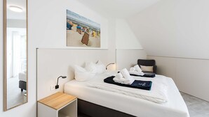Quarto de hotel moderno com cama, mesa de cabeceira, pintura na parede e um espelho grande.