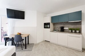 A compact kitchen with a dining area, a flat-screen TV, and a built-in oven. - MEERholung Vacation Rental 3.1: Beachfront Studio with Balcony - MEERholung House (Cuxhaven)