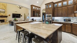 Une cuisine spacieuse dotée d’un grand îlot central, de meubles en bois et d’appareils électroménagers modernes.