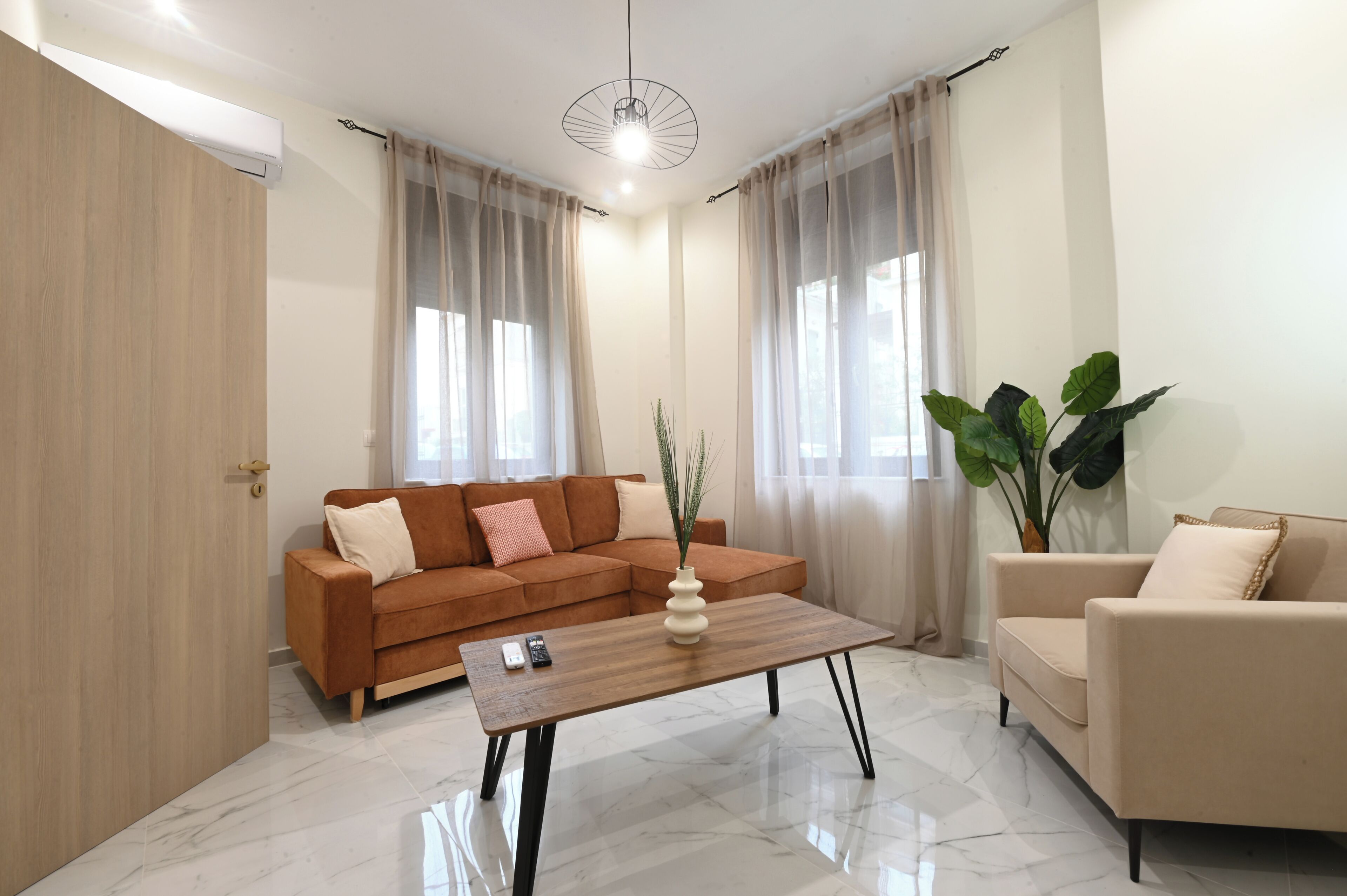 A modern living room with a sofa, a coffee table, a chair, and a large plant.