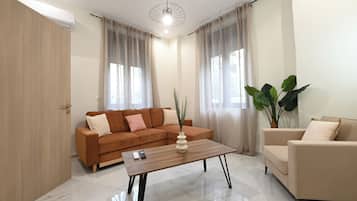 A modern living room with a sofa, a coffee table, a chair, and a large plant.