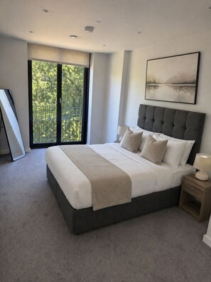Ein modernes Schlafzimmer mit einem großen Bett, einem Balkon und einem Bild an der Wand.