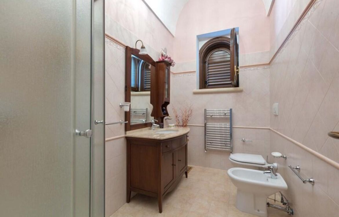 Ein Badezimmer mit einem Holzkonsolenbecken, einem Waschbecken, einer Toilette und einem Bidet.