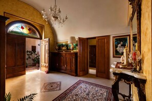 A grand hallway with a chandelier, wooden doors, a stained glass window, and a large mirror. - Villa Raffaella _ Spongano (Spongano)