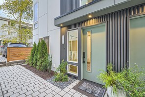 A modern building with a paved entrance, a wooden fence, and potted plants. - Modern Townhome with Private Parking - Near Lumen Field, Downtown & Cap Hill (Seattle)