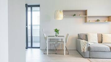 A modern living room with a dining table, chairs, a sofa, and built-in shelves.