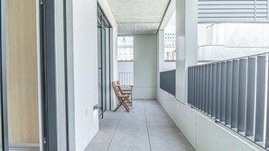 A narrow corridor with a wooden door, a chair, and a metal railing. - 1BR Apartment Near Airport with Parking (Bratislava)