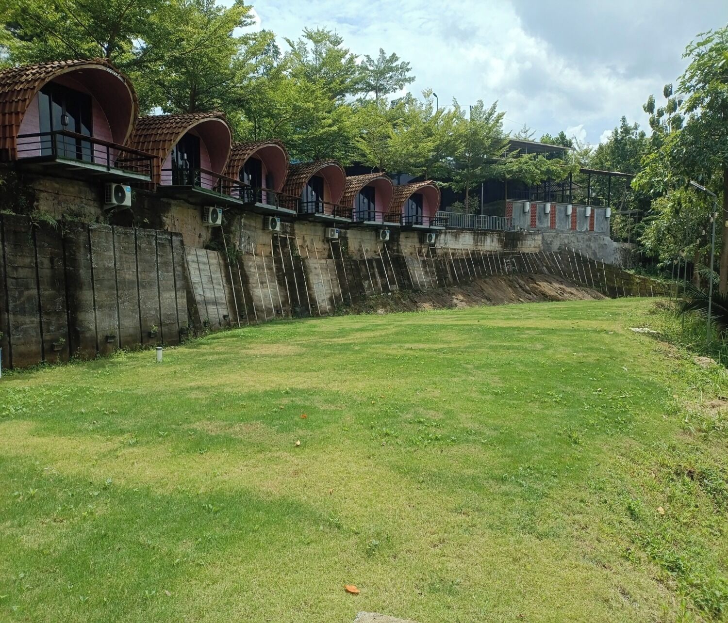 A row of rustic, arched-roofed structures with a grassy area in front.