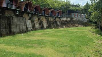 A row of rustic, arched-roofed structures with a grassy area in front.