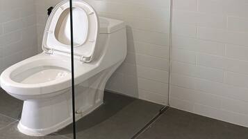 A white toilet with a closed lid in a bathroom with white tiled walls and dark floor tiles.