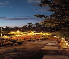 Um caminho serpenteia por um jardim com vários arcos e luzes de corda.