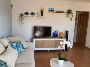 A living room with a sofa, TV, and decorative items including fish sculptures and a plant. - Casa Azul, an oasis of peace and tranquility (Lajares)