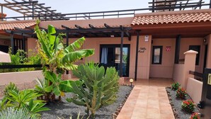 Entrada de un hotel con un camino empedrado, un letrero que dice 'Villa Azul' y un área cubierta con plantas.