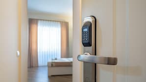 A modern hotel room door with a digital keypad lock, a visible bed, and a window with curtains. - Relaxation and comfort within walking distance of everything, ideal for families, couples and small groups (Palermo)
