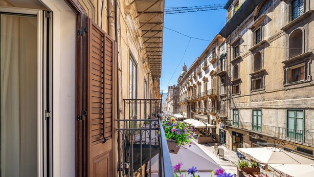 A narrow street with buildings on both sides, outdoor seating with umbrellas, and a balcony with a flower planter. - Relaxation and comfort within walking distance of everything, ideal for families, couples and small groups (Palermo)