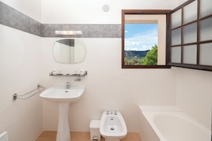 A bathroom with a sink, bidet, and a window with a view of mountains. - Hotel Restaurant Le Verdon (Les Salles-sur-Verdon)