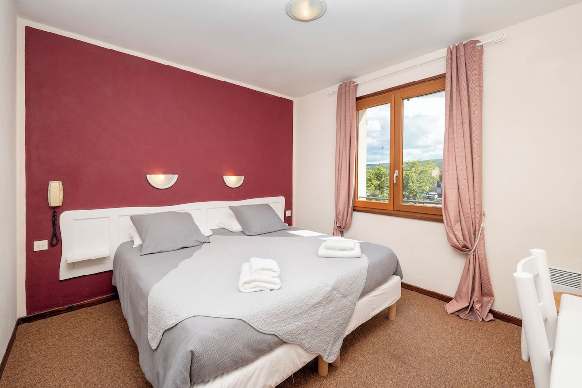 A bedroom with a bed, a bedside telephone, and a window with curtains.