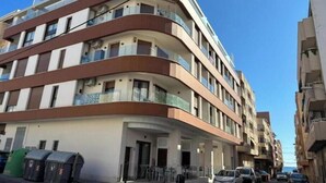 Un hotel de varios pisos con balcones, una entrada cubierta y un área de estacionamiento.