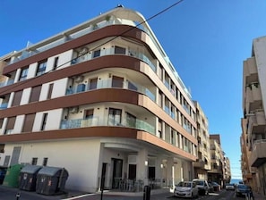 A multi-story hotel with balconies, a covered entrance, and a parking area. - Apartment with rooftop pool 150 m from the beach (03193 San Miguel des Salinas)