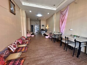 A spacious living area with a long sofa, a dining table, and a kitchen in the background. - Lexis Residence Patong - Newly Renovated (Patong)