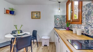 Cocina compacta con comedor, un pequeño bote de basura y una ventana con vistas.