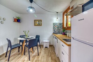 A compact kitchen with a dining area, a white refrigerator, and a wooden countertop.