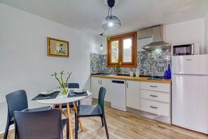 Una cocina moderna con armarios blancos, lavavajillas, microondas y un comedor con mesa y sillas.