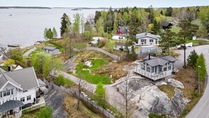A residential area with houses, a dock, and a lake. - Hilltop house overlooking ocean sunrise and sunset (Vaxholm)