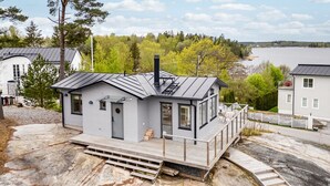 A modern house with a balcony, a chimney, and a view of a lake. - Hilltop house overlooking ocean sunrise and sunset (Vaxholm)