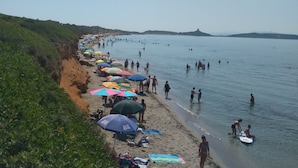 A beach with people, umbrellas, and a clear sky.