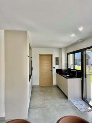 A modern kitchen with a wooden door, a black countertop, and a window. - Bright, quiet house near the beach. (Saint-Lunaire)