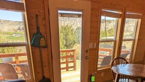 A wooden interior with a sofa, a dining table, and a view of the outdoors through a door.