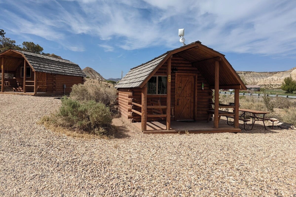 A rustic log cabin with a porch, a small window, and a door.
