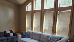 A living room with a sectional sofa, a smaller sofa, and a ceiling fan.