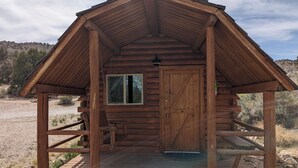 A wooden cabin with a pitched roof, a front door, and a small window.