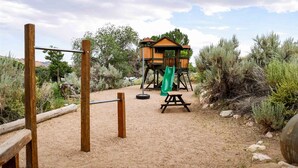 A playground with a slide and a swing set in a natural setting.