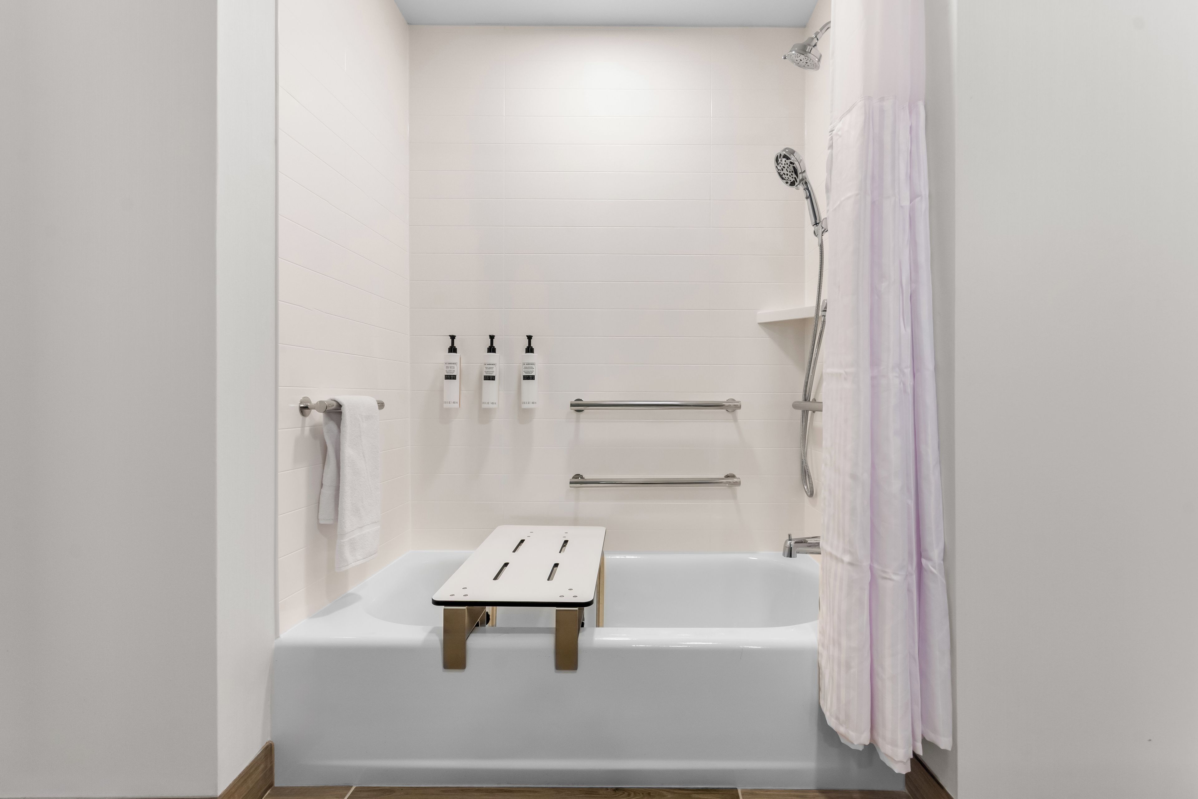 A modern bathroom with a bathtub, a shower, and a towel rack.