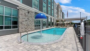 A hotel pool area with a stone wall, a blue water feature, and a flag.