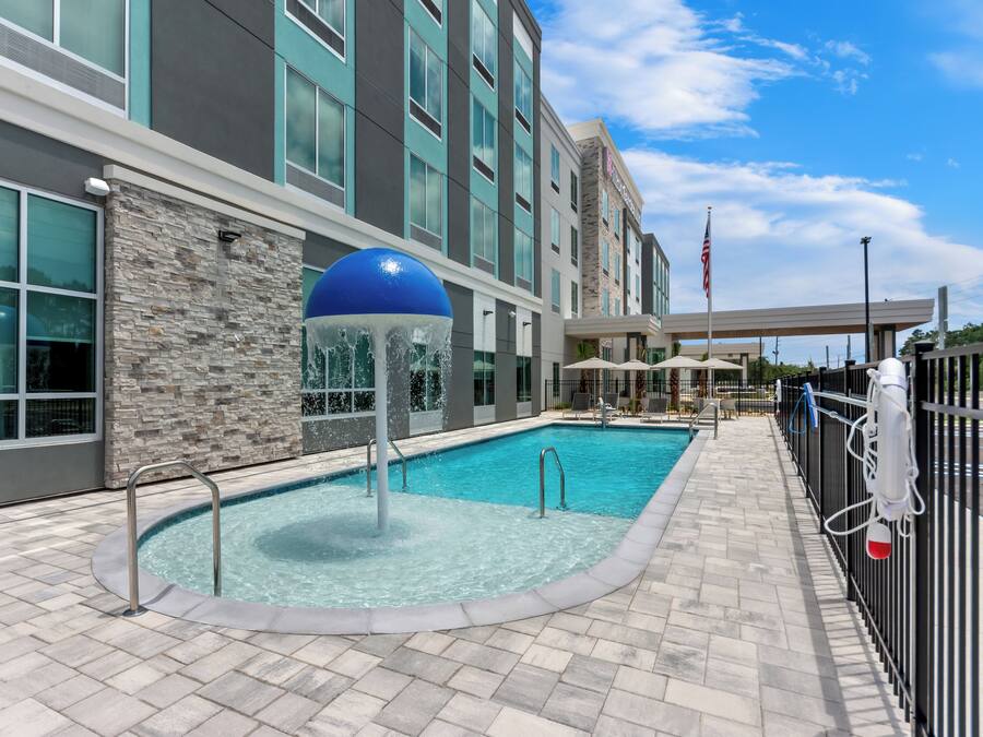 A hotel pool area with a stone wall, a blue water feature, and a flag.