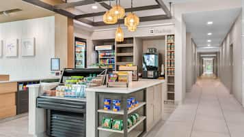 A clean, modern convenience store with a self-serve beverage station, shelves stocked with snacks and beverages, and a visible checkout area.