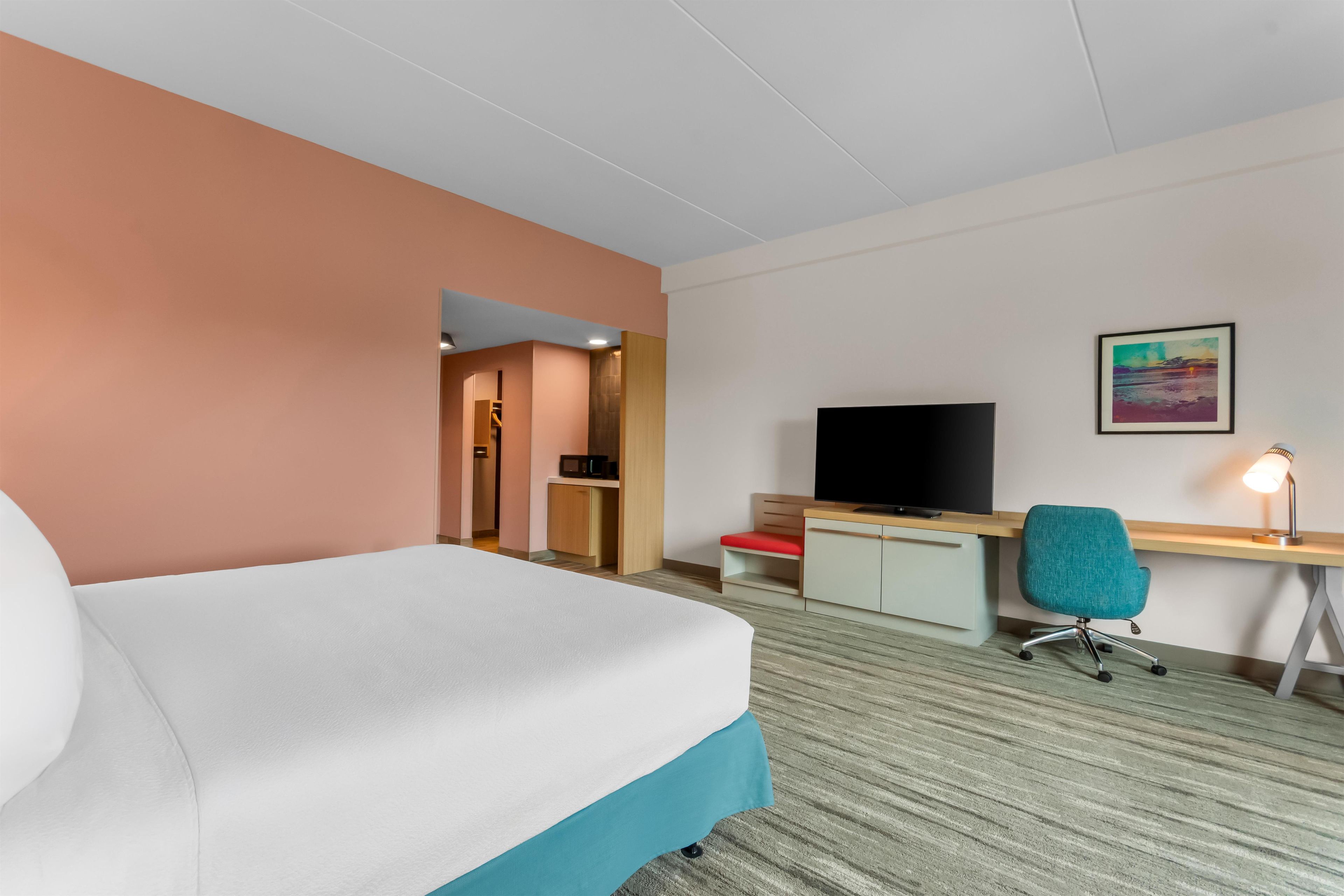 A hotel room with a bed, a desk with a computer, a television, and a chair.