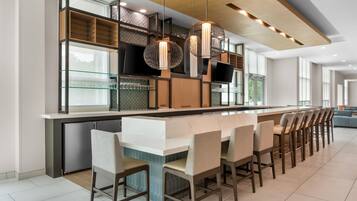 A modern kitchen with a long island, bar stools, and pendant lighting.