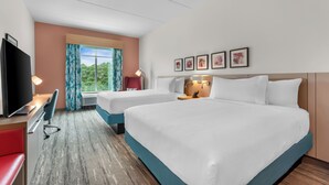 A hotel room with two beds, a desk, a TV, and a window with curtains.