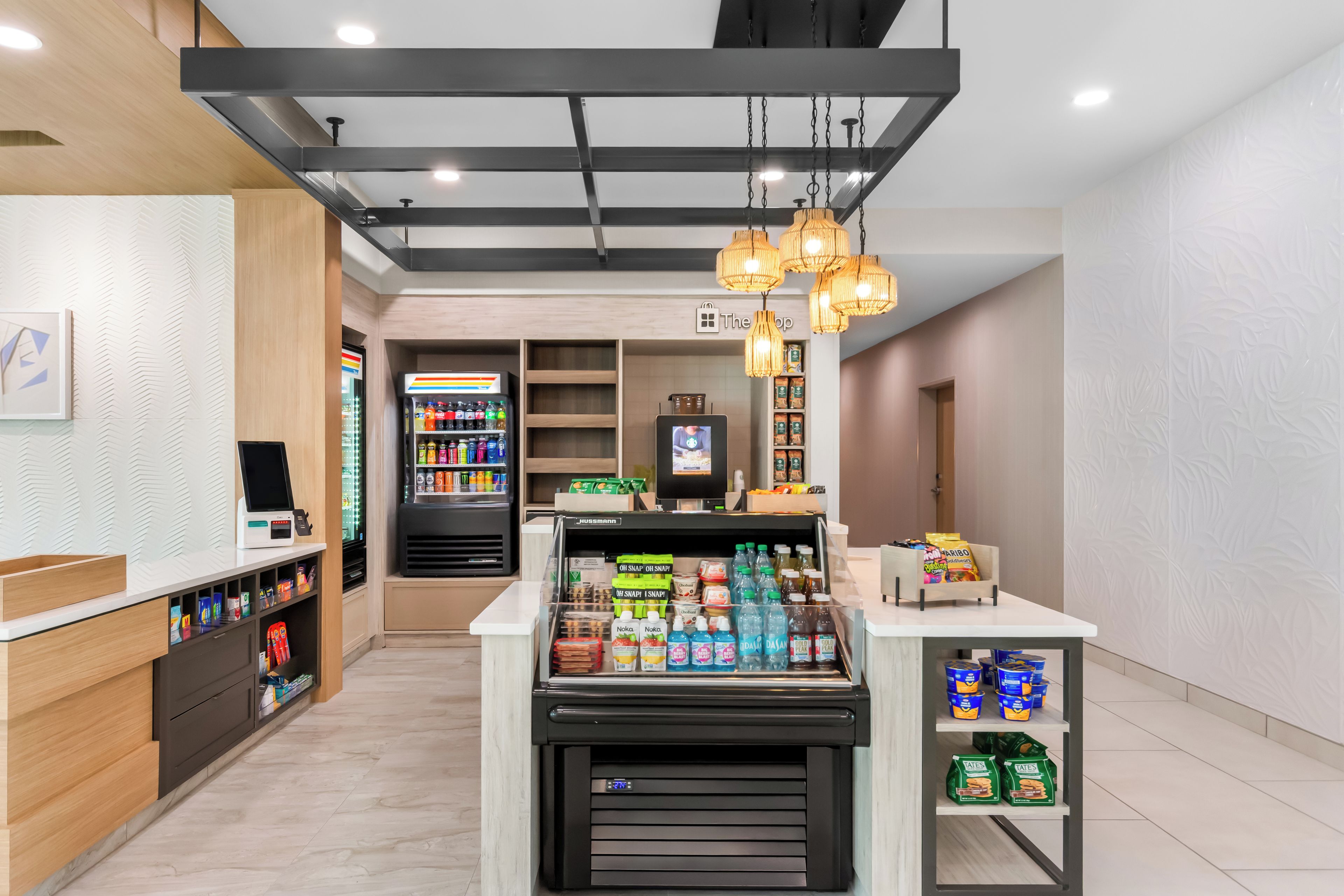 Ein modernes Supermarkt-Interieur mit einer Selbstbedienungsgetränkestation, gekühlten Getränken und Snackregalen.