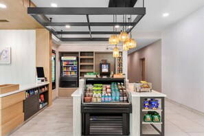 Interior moderno de una tienda de conveniencia con autoservicio de bebidas, refrigeradores con bebidas y estantes con snacks.
